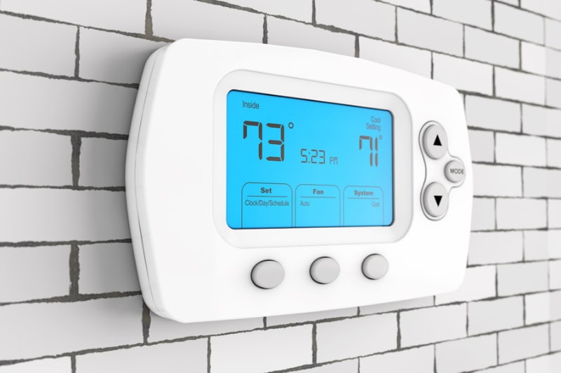 Thermostat mounted on a wall with a blue light.