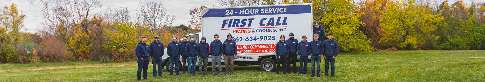 First call team standing in front of service truck.